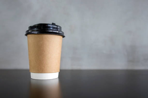 istock closeup paper cup of coffee on black table with soft-focus and over light in the background 1237700741