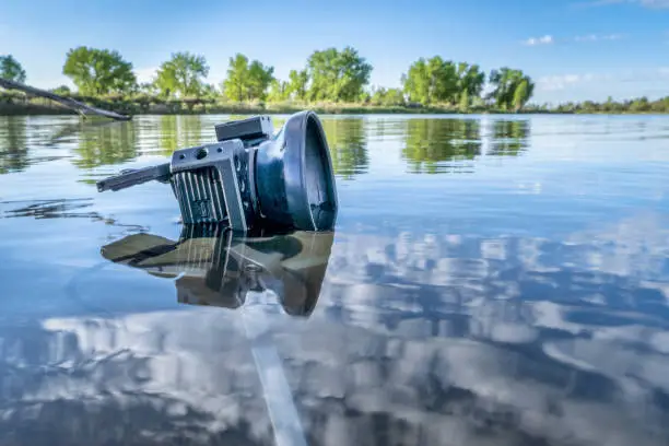 small waterproof action camera in a rugged cage partially submerged with a mini tripod in a calm lake, morning spring scenery in Colorado