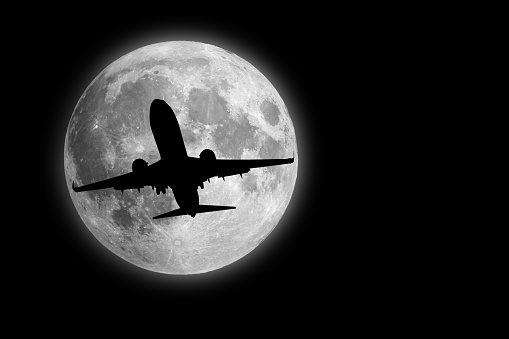 Night flight, silhouette aircraft flying cross the moon
