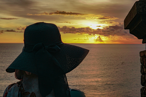 Picture of a alone girl looking at the sunset from sunset point at Uluwatu Temple in Bali Indonesia