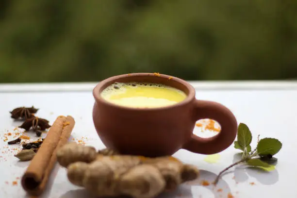 Turmeric golden milk in a cup with ginger, cinnamon,blackpepper and turmeric powder