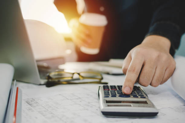 istock hand of engineer and architect calculate on digital calculator and blueprint on workplace desk in meeting room project at construction site office, contractor, engineering and construction concept 1237785411