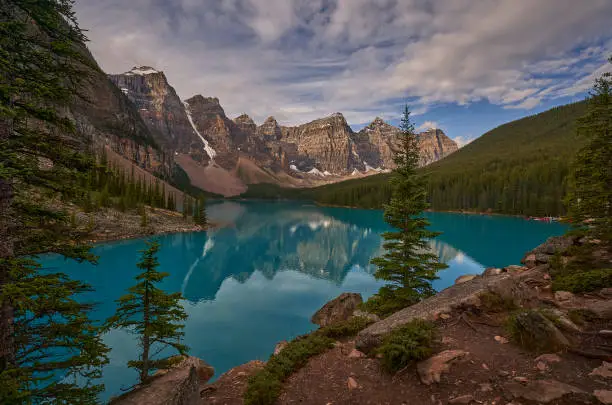 Photo of Trees with reflection in Moraine Lake in Canada