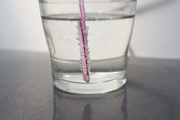 Glass of straw sparkling water angled straw and bubble water soda water glass lemon stock pictures, royalty-free photos & images