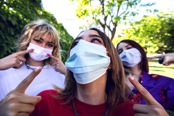 istock Group of teenagers posing showing their protective face masks 1237840062