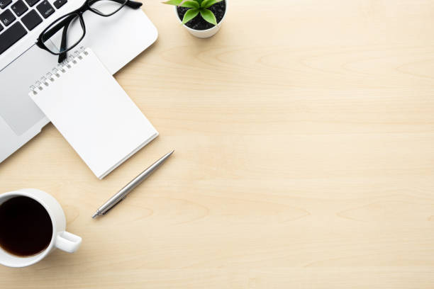istock Wood office desk table with blank notebook over laptop computer with pen, cup of coffee and supplies. Top view with copy space, flat lay. 1237845922