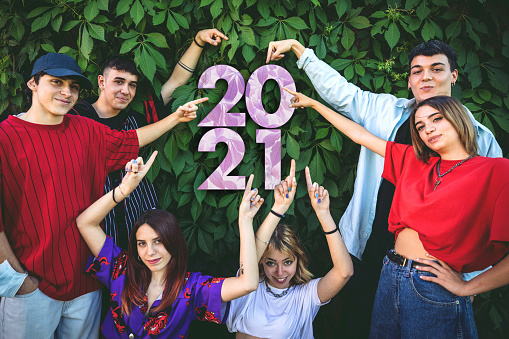 Friends celebrating new year's eve pointing on 2021