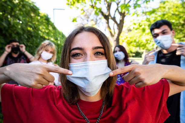 istock Group of teenagers posing showing their protective face masks 1237861146