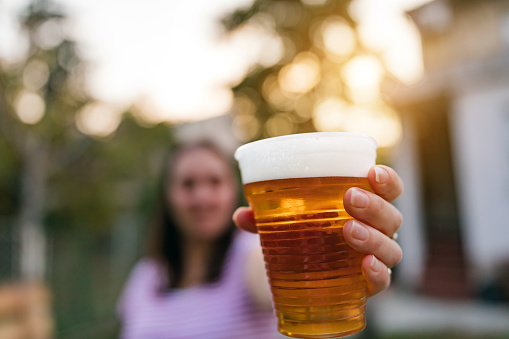 Woman holding cold glass of beer outdoors.