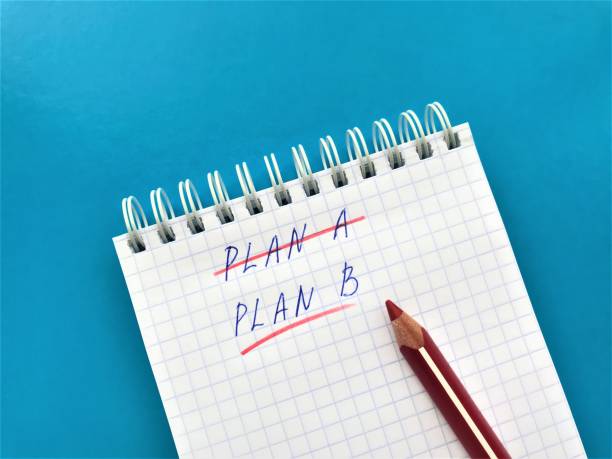 istock In a spiral notebook in a cell crossed out with a red pencil Plan A, underline Plan B. Red pencil is on the notebook, all on a bright blue background 1237862213