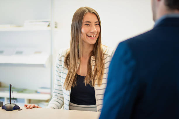 istock Female Team Assistant at Front Desk talking with Businessman 1237864351