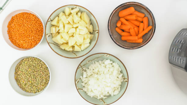 l’oignon haché, les pommes de terre hachées, les carottes et les lentilles se ferment dans des bols, vue d’en haut. recette de soupe de lentilles, ingrédients sur la table de cuisine - carrot close up silverware cutting board photos et images de collection