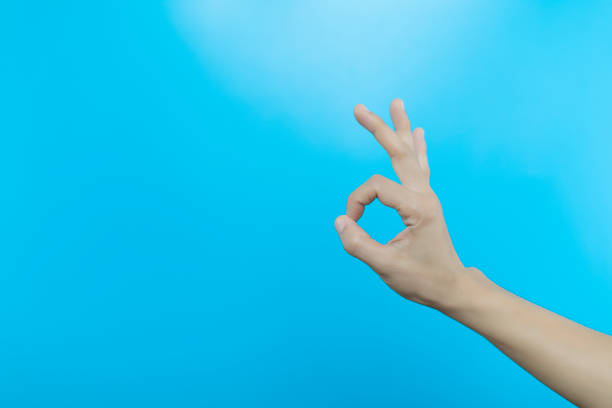 istock Women hand show gesturing  sign on light blue background. human hand make OK sign on blue background with copy space. 1237883084