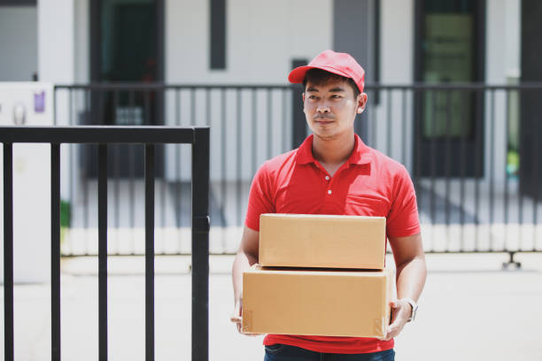 istock Red deliveryman holding cardboard box at customer home 1237922644