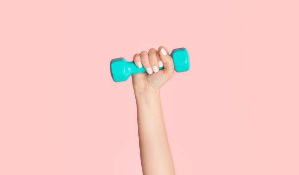 istock Unrecognizable female athlete with dumbbell on pink background, close up. Panorama 1237974574