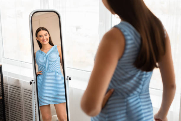 dziewczyna w nowej sukience patrząc na lustro pozowanie w domu - mirror women dress looking zdjęcia i obrazy z banku zdjęć