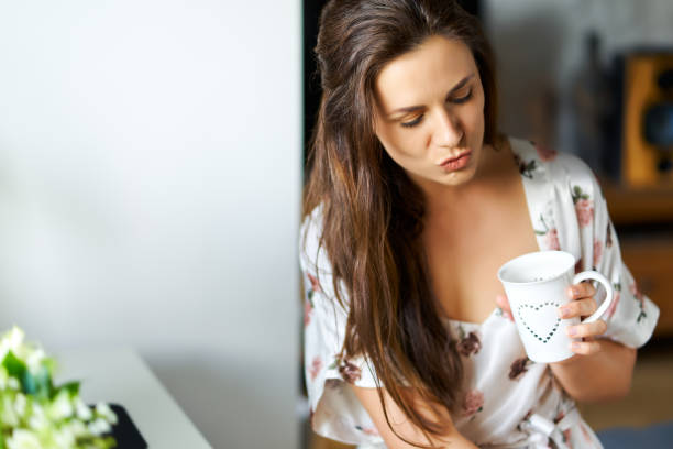 istock beautiful woman in pajamas drinking water from a cup at a desk 1237982054