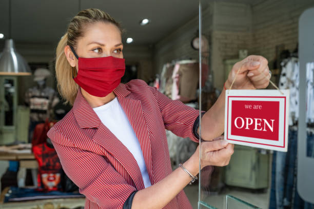 istock Happy business owner hanging an open sign during COVID-19 1237982292