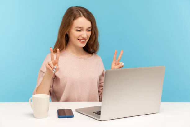 istock Happy successful young woman showing victory gesture and smiling into laptop screen, talking online video call 1238007701