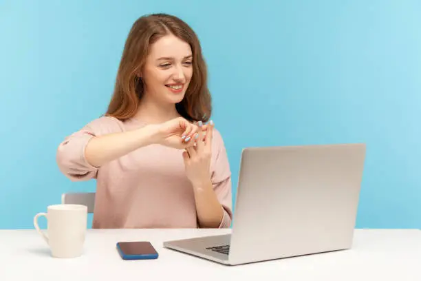 Photo of Positive manager, woman employee showing hashtag symbol while talking on video call with client, communicating online