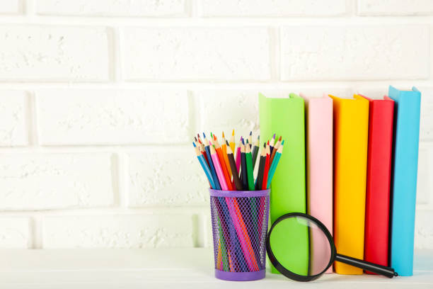 istock Multi coloured school books and stationery on white brick wall background 1238008075