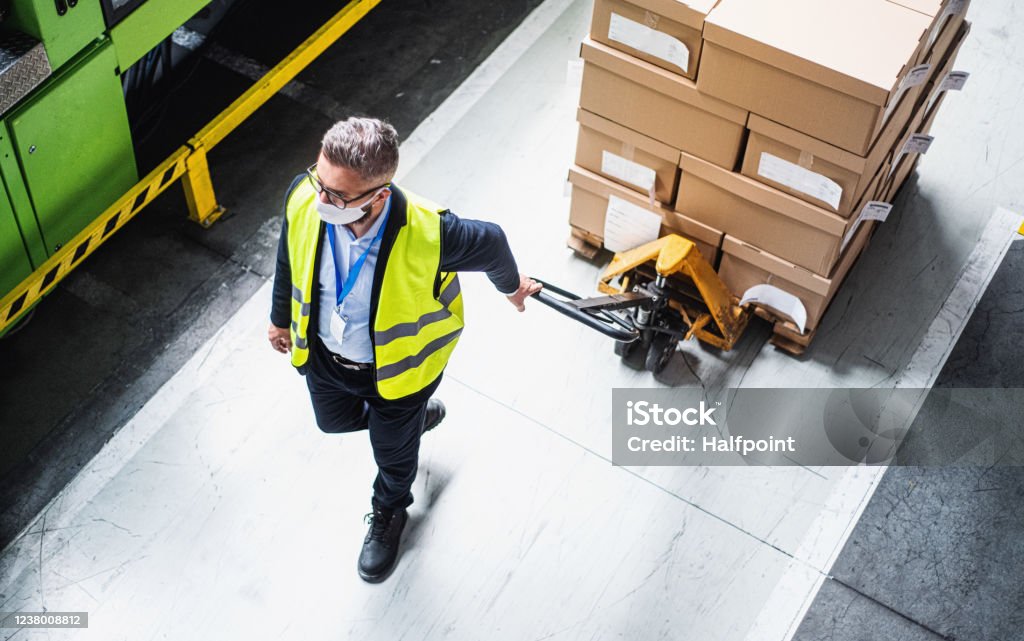 Top view of man worker with protective mask working in industrial factory or warehouse. Top view of man worker or technician with protective mask working in industrial factory or warehouse. Warehouse Stock Photo