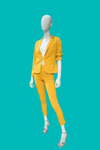 Full length female mannequin dressed in fashionable yellow trouser suit isolated. No brand names or copyright objects.