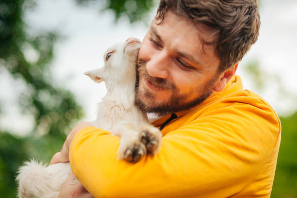 istock Young Man Holding Baby Goat 1238064965