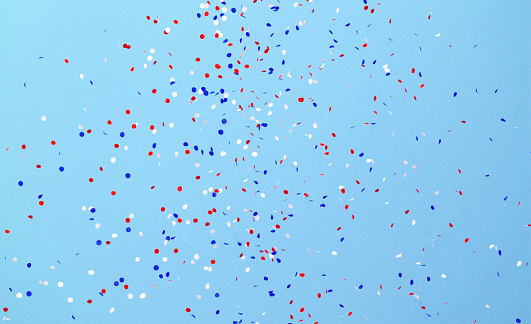 Circle shaped paper confetti in USA flag color falling over blue background. Great use for party and us elections concepts.