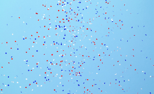 Circle shaped paper confetti in USA flag color falling over blue background. Great use for party and us elections concepts.