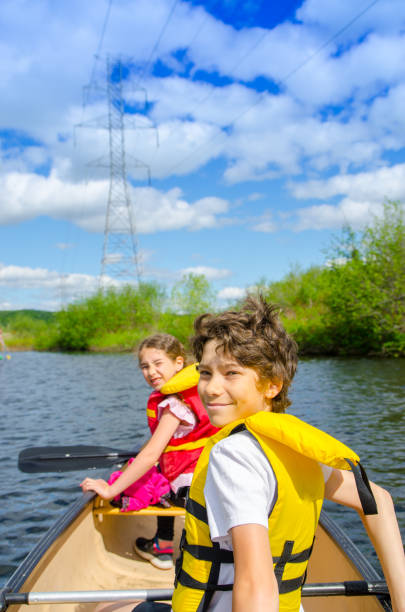 A smiling 12 year old boy paddling in a small kayak.