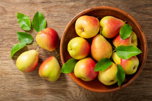istock fresh pears with leaves in a bowl on a wooden table, top view 1238088156