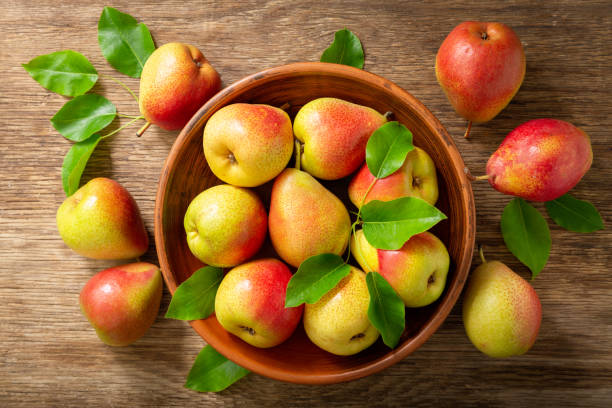 istock fresh pears with leaves in a bowl on a wooden table, top view 1238088670