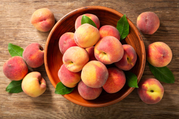 istock fresh ripe peaches with leaves in a bowl, top view 1238088675