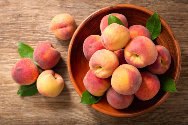 istock fresh ripe peaches with leaves in a bowl, top view 1238088696