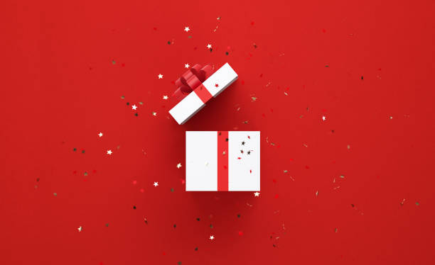 Star Shaped Confetti Falling Over Open White Gift Box Tied With Red Ribbon Star shaped confetti falling over white gift box tied with red ribbon on red background. Horizontal composition with copy space, Great use for Christmas and Valentine's Day related gift concepts. unwrapping stock pictures, royalty-free photos & images