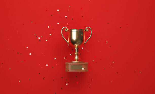 istock Star Shaped Concetti Falling over Gold Cup Sitting over Red Background 1238100211