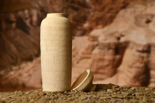 A model of a Jar used for the Dead Sea scrolls against a blurred background of the Qumran caves