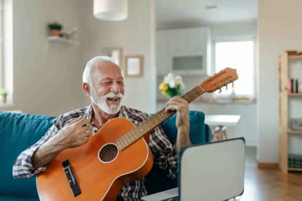 istock Elderly man learns to play acoustic guitar online using a Laptop 1238194784