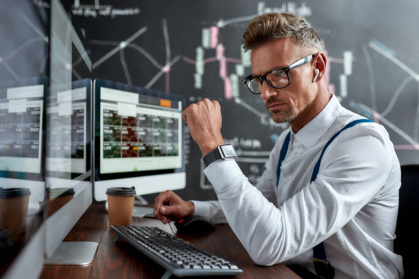 sua vida, sua potencialidade. empresário elegante, comerciante sentado na frente do monitor de computador enquanto trabalhava usando fones de ouvido sem fio. quadro negro cheio de gráficos e análises de dados em segundo plano. - stock certificate audio - fotografias e filmes do acervo