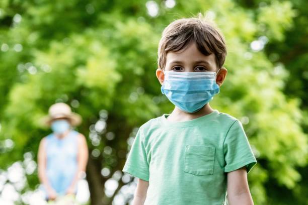istock Little boy wearing a protective face mask looking at the camera 1238233131