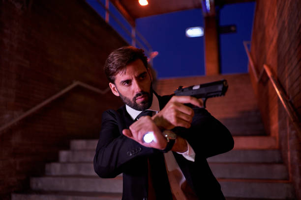 istock Man dressed in formal wear holding his gun out while going underground 1238244008