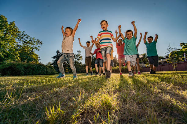 istock Kids with hands raised running in public park 1238246103