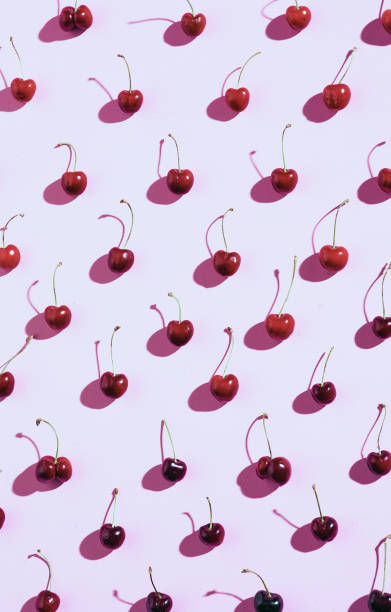 istock Fresh cherry berries are laid out in a pattern on a lilac background with harsh light and shadows, a bright poster. 1238250306