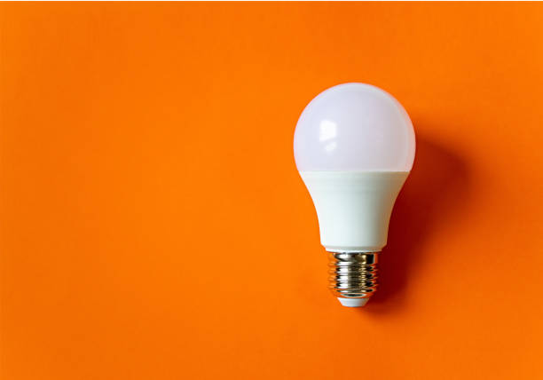 vit energibesparande glödlampa på en orange bakgrund med kopieringsutrymme. led vit glödlampa, begreppet ny idé - led lampa bildbanksfoton och bilder