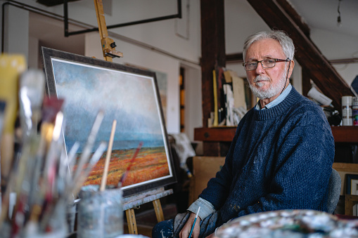 Expert senior artist sitting in his home workshop