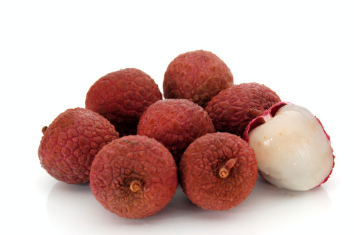 Lychees with cut fruit over wooden table.