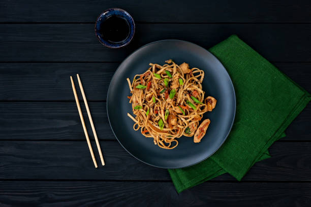 asian udon noodles with chicken vegetables and teriyaki sauce on a black wooden background. chinese and japanese cuisine. - clothing traditional culture chinese culture black imagens e fotografias de stock