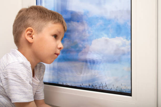 istock A child sits on a windowsill and looks out the window while waiting 1238293170