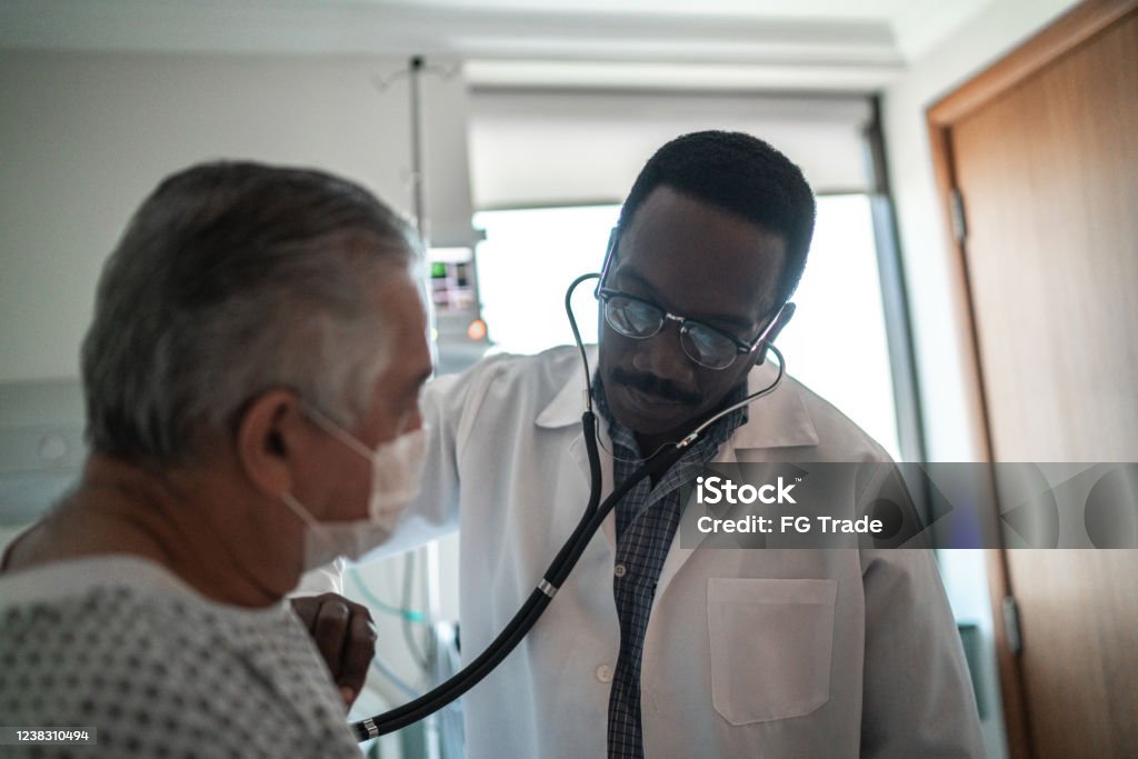 Врач слушает сердцебиение пациента в больничной палате - Стоковые фото Кардиолог роялти-фри